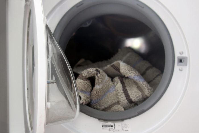 Washing Machine open with a gray bath mat in the drum
