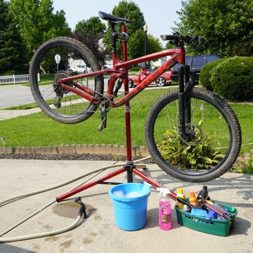 bike on a stand in the driveway with cleaning products surrounding it