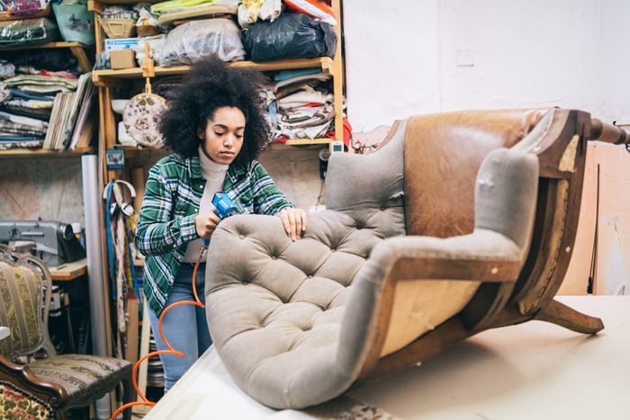 young woman Refurbishing a Chair In Upholstery Workshop