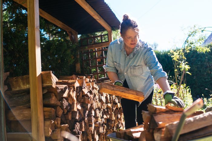 woman stacking firewood outside in preparation for winter