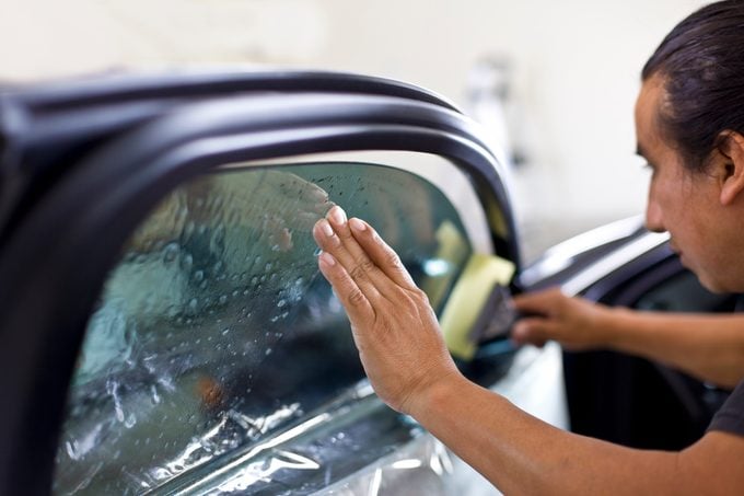 Man installing window tinting on car.