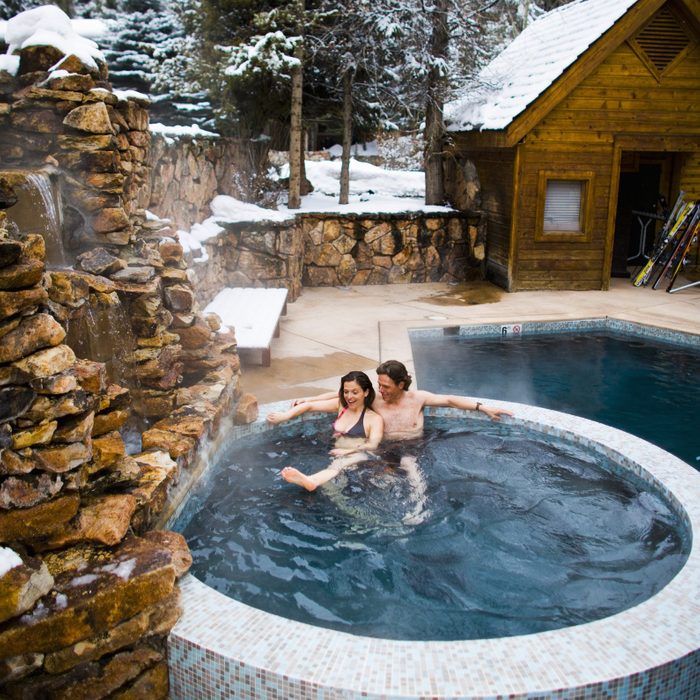 couple sitting in hot tub at winter cabin