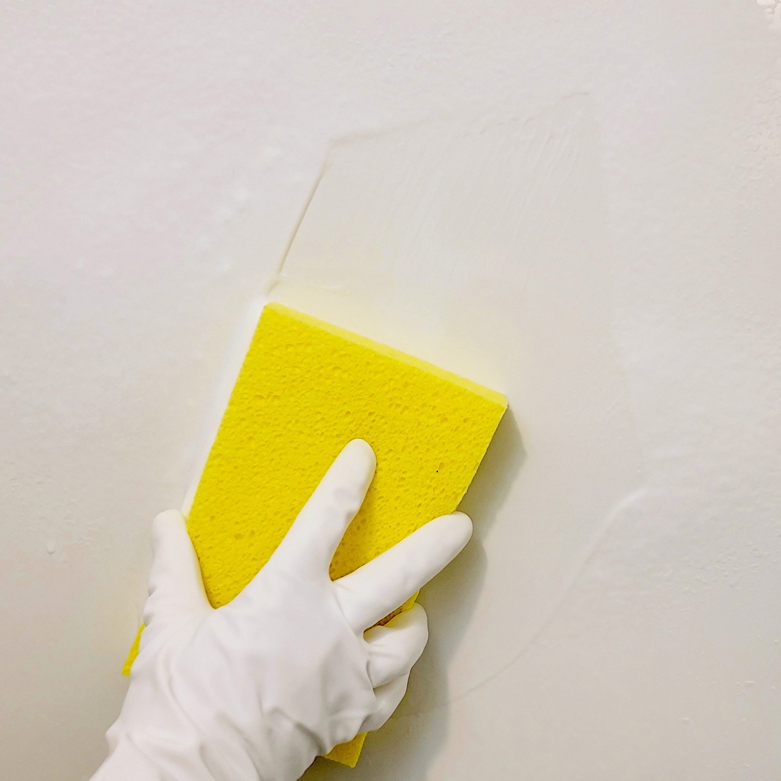 cleaning the shower walls with a yellow sponge