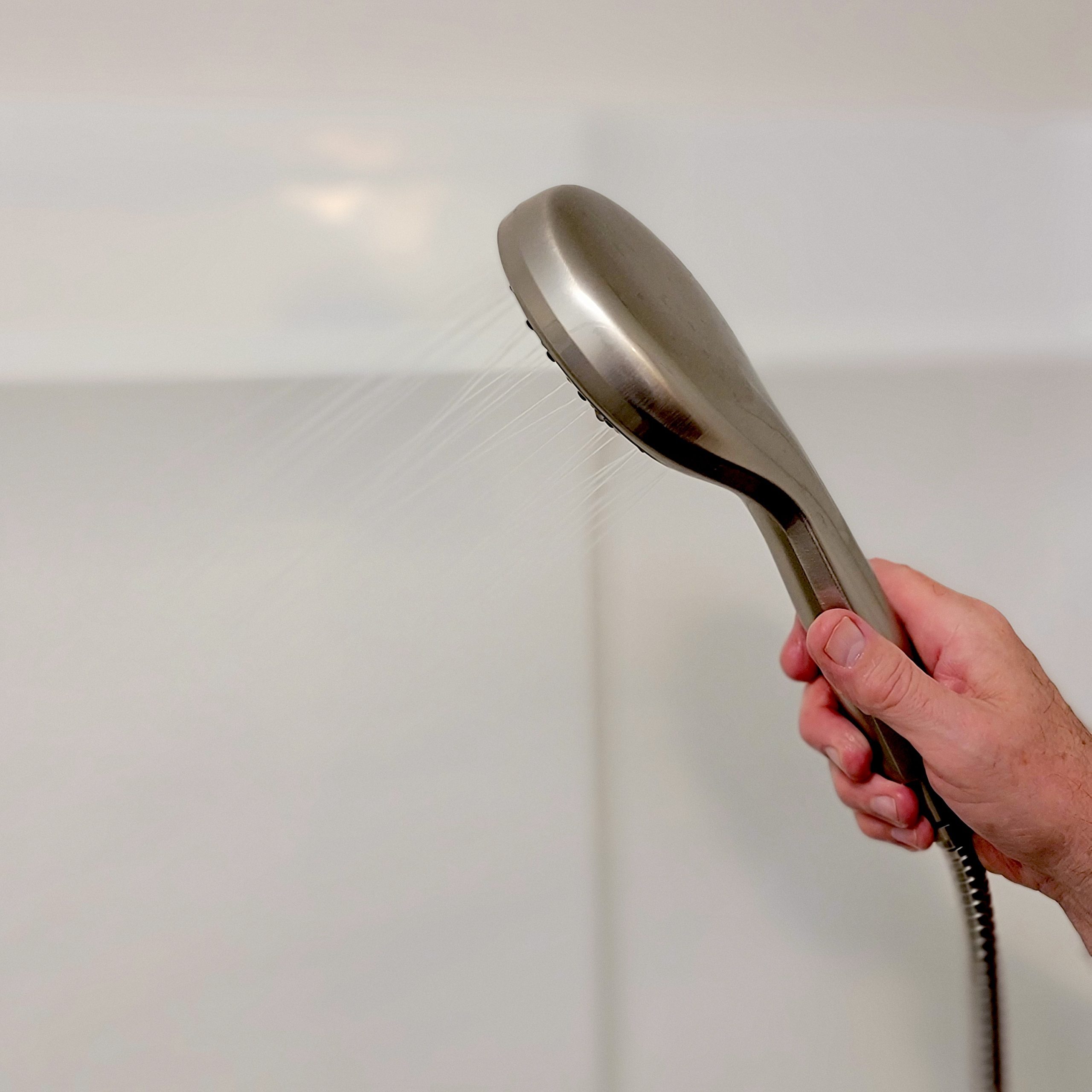 rinsing the shower walls with shower head