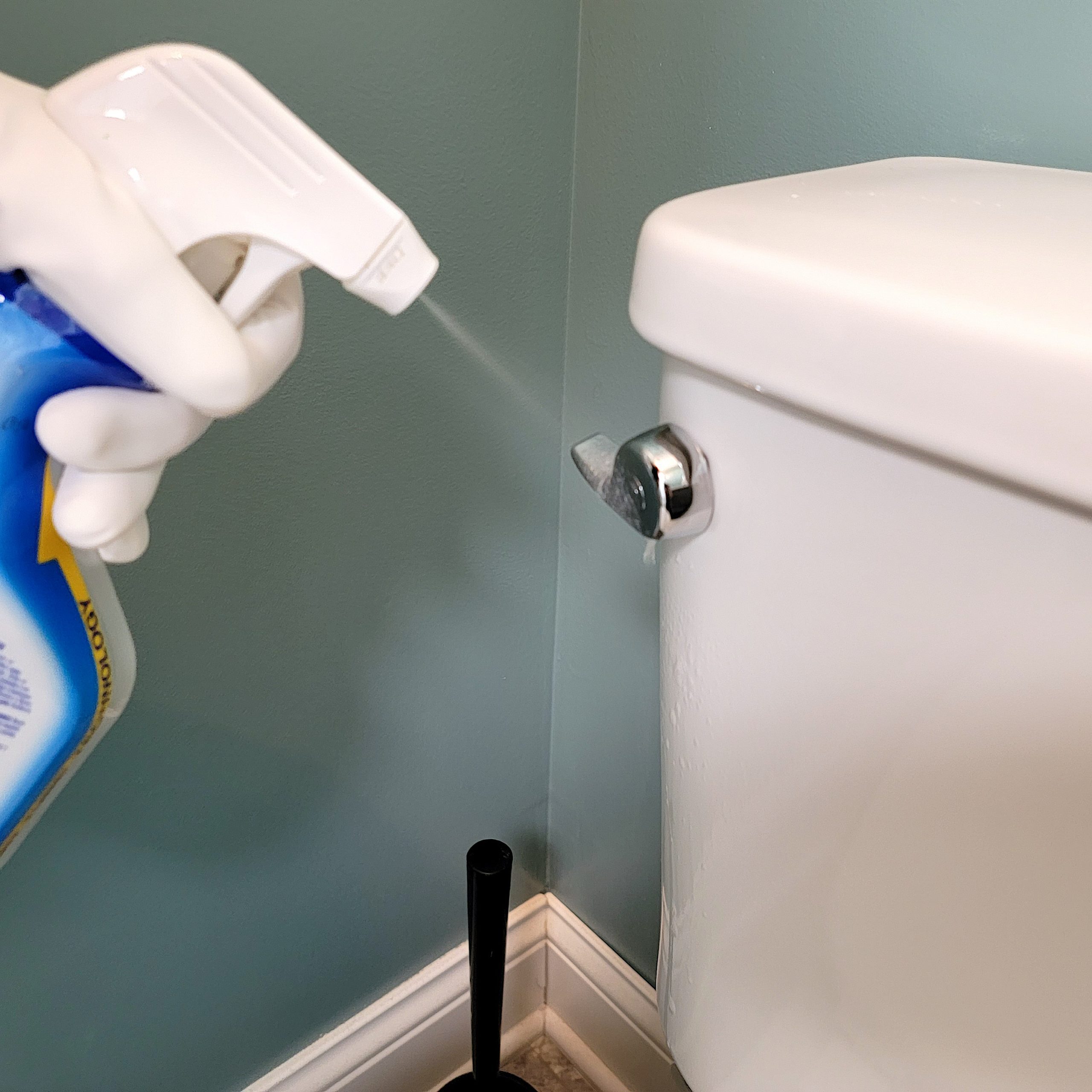 spraying the toilet handle with clorox toilet cleaning spray