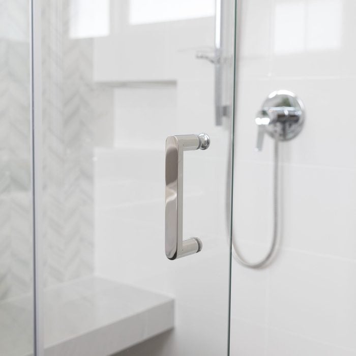 Shower room of a bathroom with glass door and chrome handle.