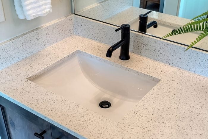 Bathroom white countertop with single basin undermount sink and black faucet