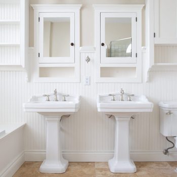 Modern and white washroom with bathtub and two mirrors