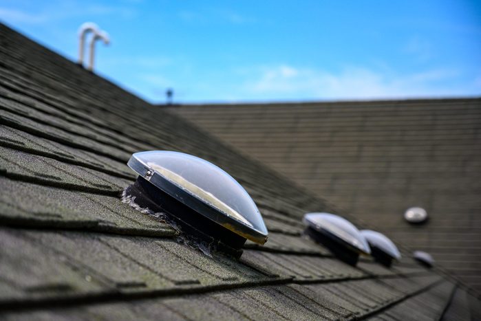 row of dome shaped solar tubular skylights installed on an asphalt shingle roof