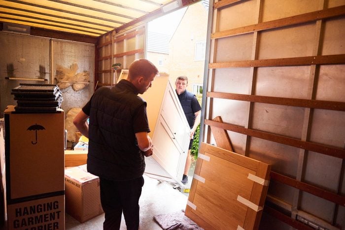 professional movers moving furniture out of moving truck into home
