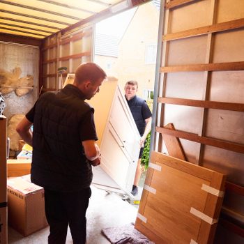 professional movers moving furniture out of moving truck into home