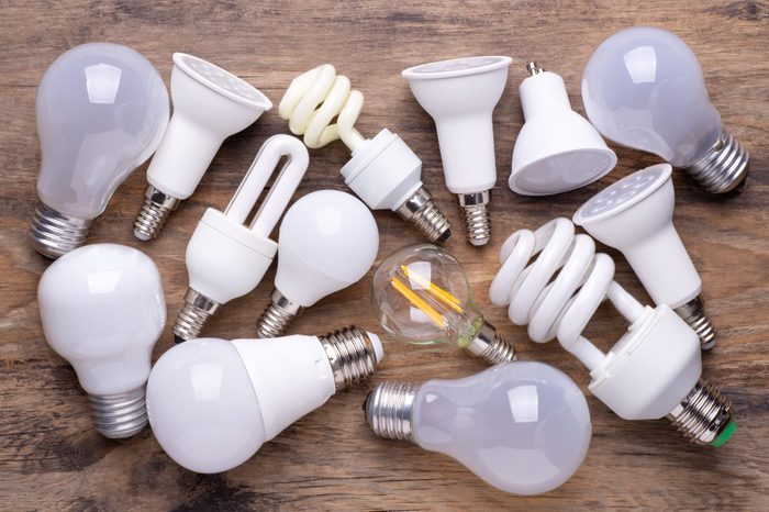 Six different kinds of light bulbs on wooden background, top view