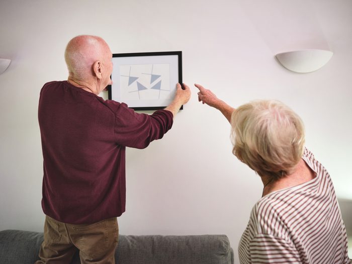 Shot of a senior couple hanging a picture on the wall of their home