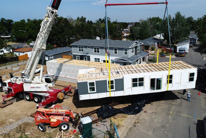 high angle view of modular home construction site. a crane brings a portion of the home into place.