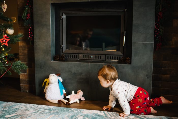 Baby plays around an electric fireplace