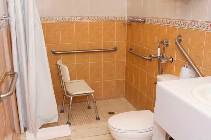 accessible bathroom in residential home with handle bars and shower chair