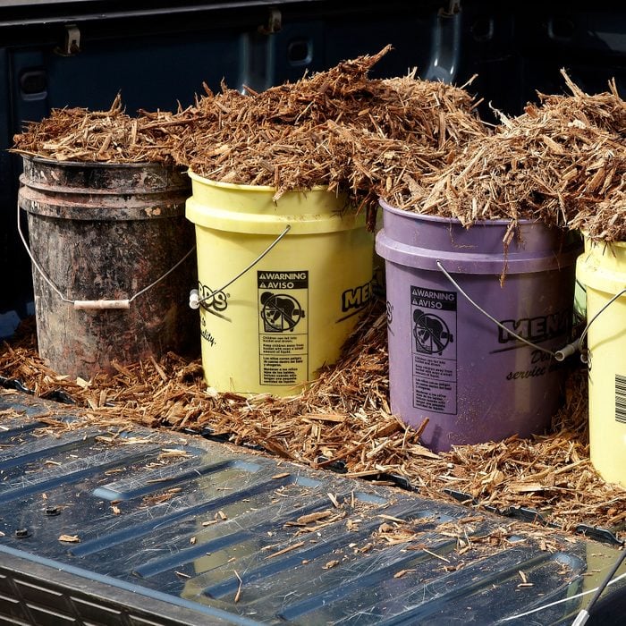many 5 gallon buckets in the back of a pickup truck with the tail gate open; mulch in the buckets in the truck bed