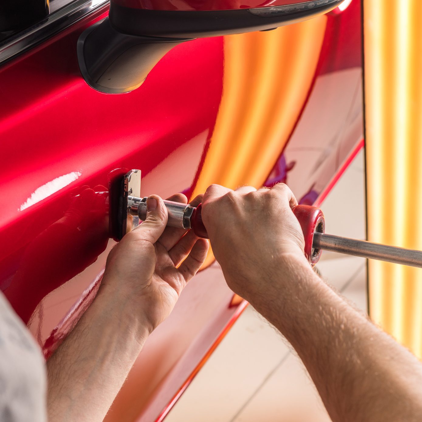 The technician removes dents on the car using the method without painting. PDR. Car body repair.