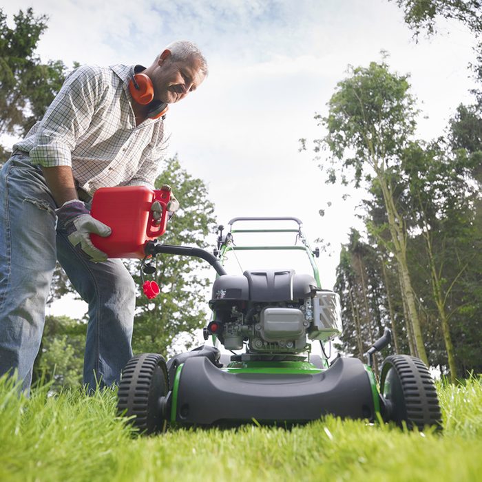 Gardener Pouring Petrol Into Lawn Mower, Surface Level View