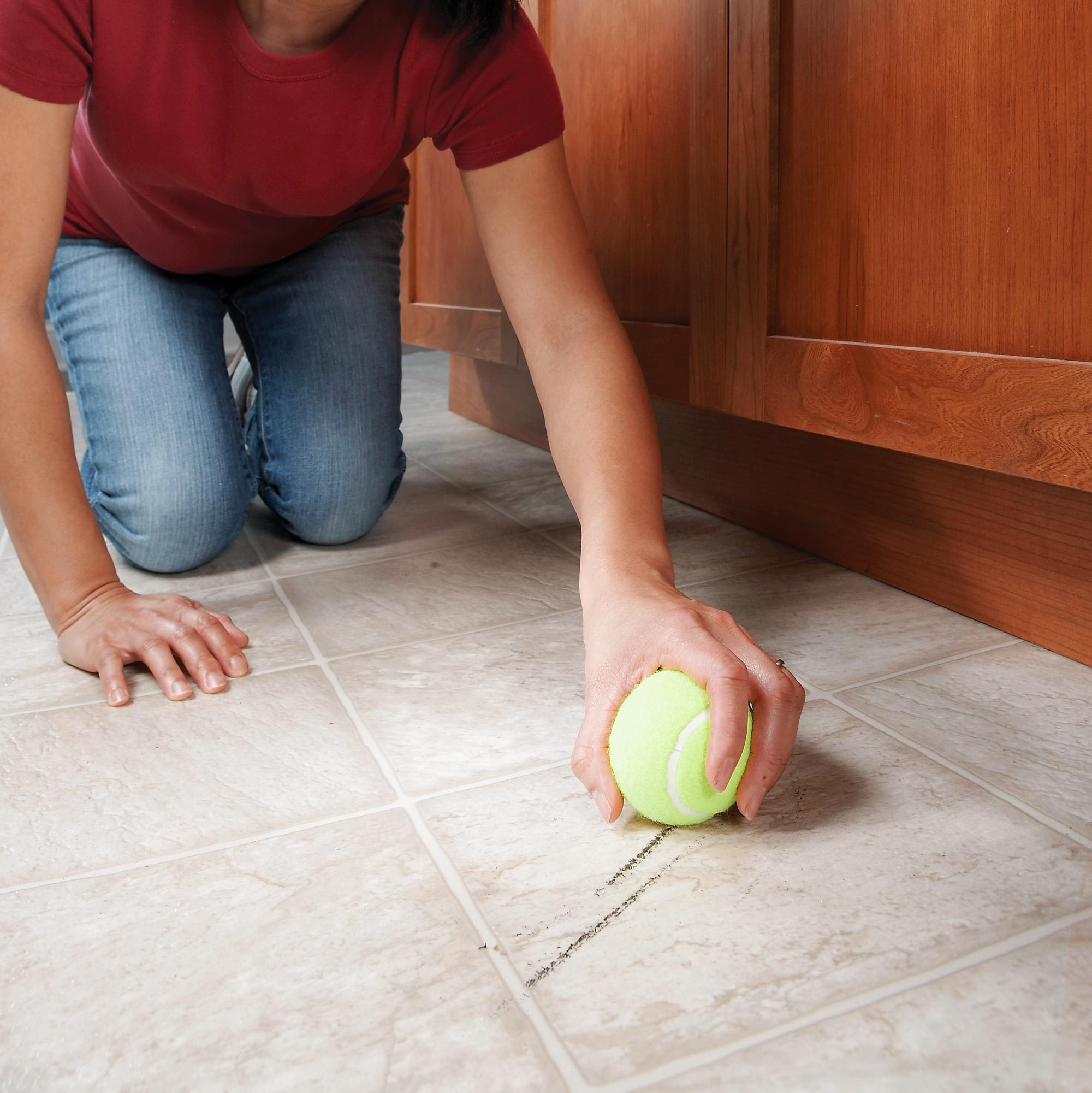 anonymous woman using a Tennis Ball to erase Scuff Marks from the floor