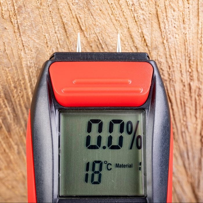 Wood moisture measurement using an electronic meter. Measurements in the home workshop. Light background.