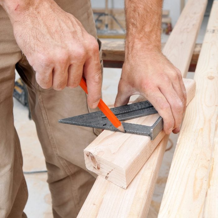 Construction Worker Using a Speed Square to Mark Stud with straight lines