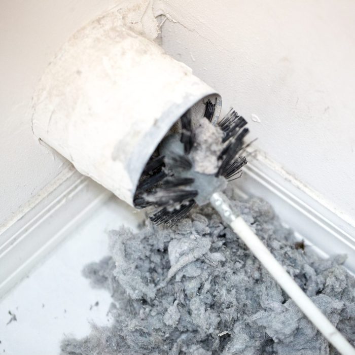 Lint being removed with a brush from a dryer vent