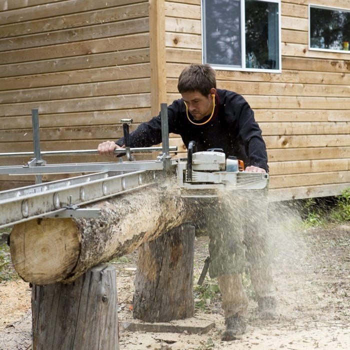 Man using chainsaw lumber maker, McCarthy, Alaska.