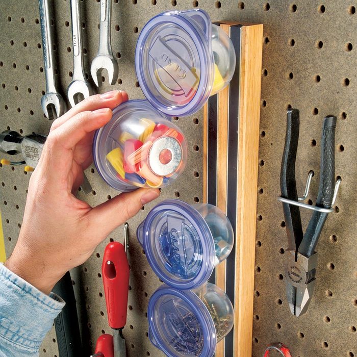 small plastic storage containers with a magnet on the bottom for storage on a pegboard with other tools