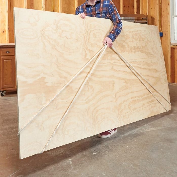 man carrying large piece of plywood