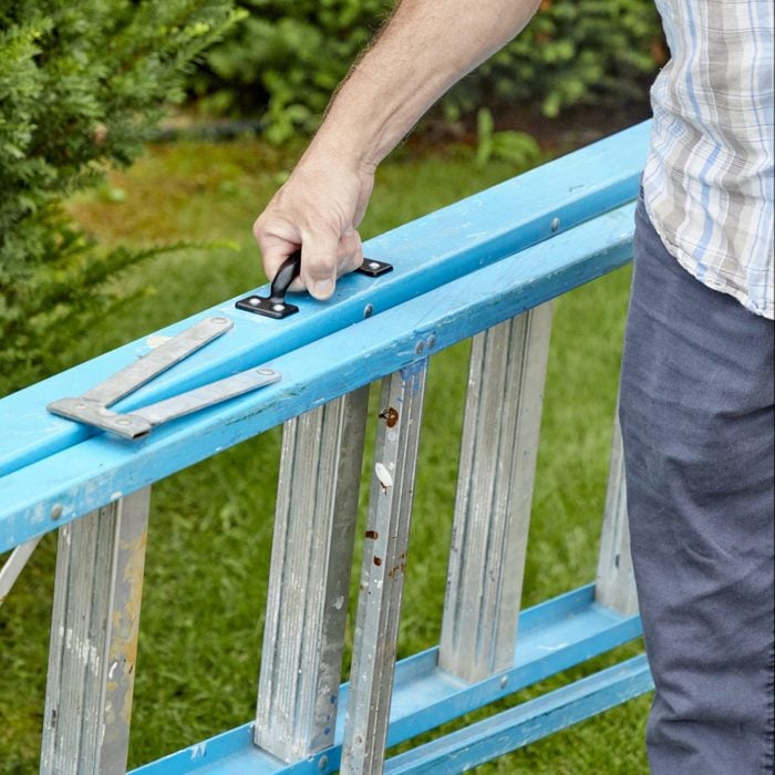 man carrying a blue ladder with a handle