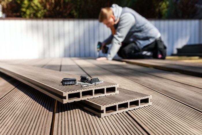 composite decking boards in the foreground with a man installing the boards in the background