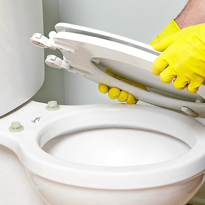 yellow gloved hands Install Detachable Toilet Seat