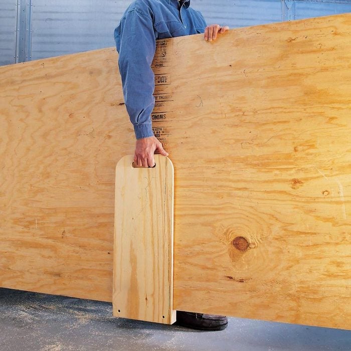 man carrying large piece of plywood with special wood carrier