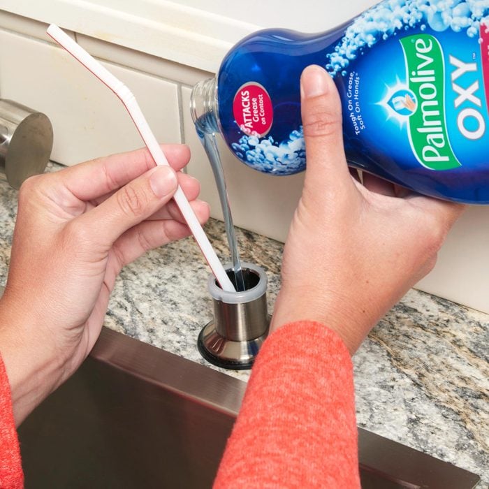 woman pouring dish soap into dispenser on counter next to sink