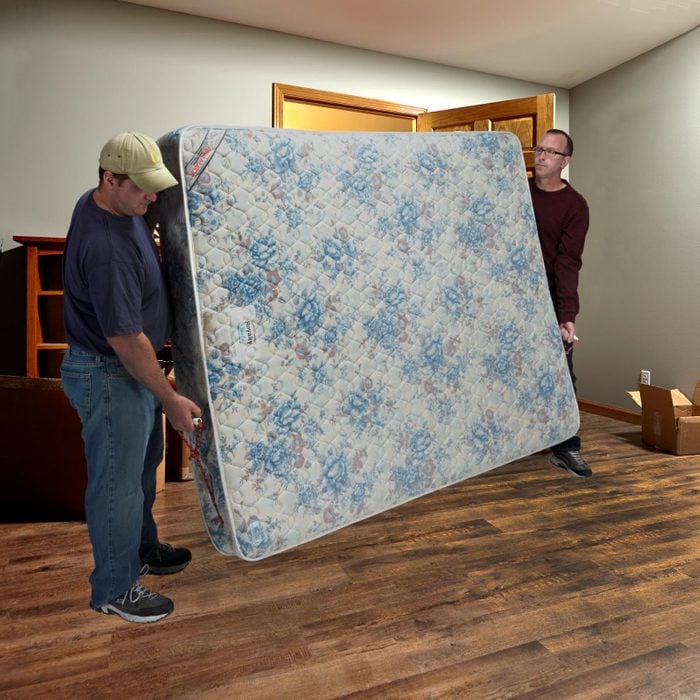 two men moving a mattress with a sling