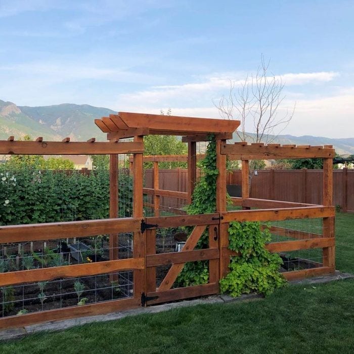 vegetable garden surrounded by well made cedar fence with wire fencing in-between the horizontal beams, mountains in the distance