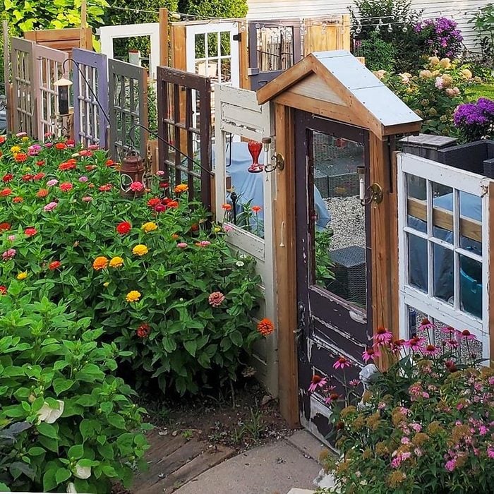 zinnia garden surrounded by a fence made from a variety of different salvaged doors
