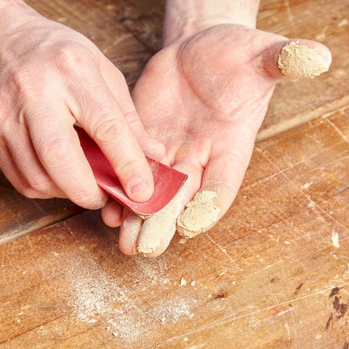 person using sandpaper to sand hands