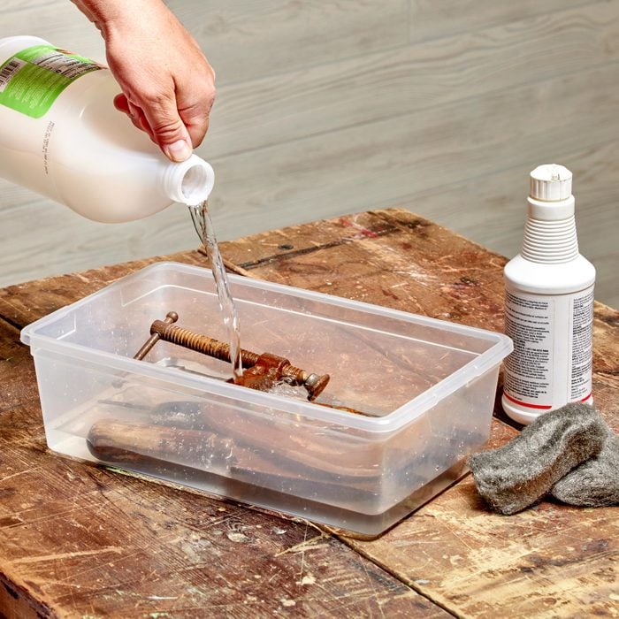 removing rust from metal tools by soaking in a plastic bin with vinegar