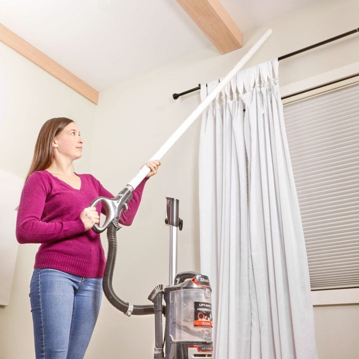 woman using a PVC pipe to extend the vacuum length for hard to reach places