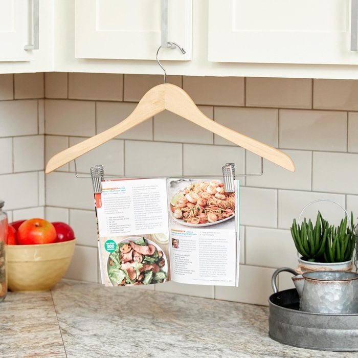 using a pant hanger in a kitchen to hang a cook book