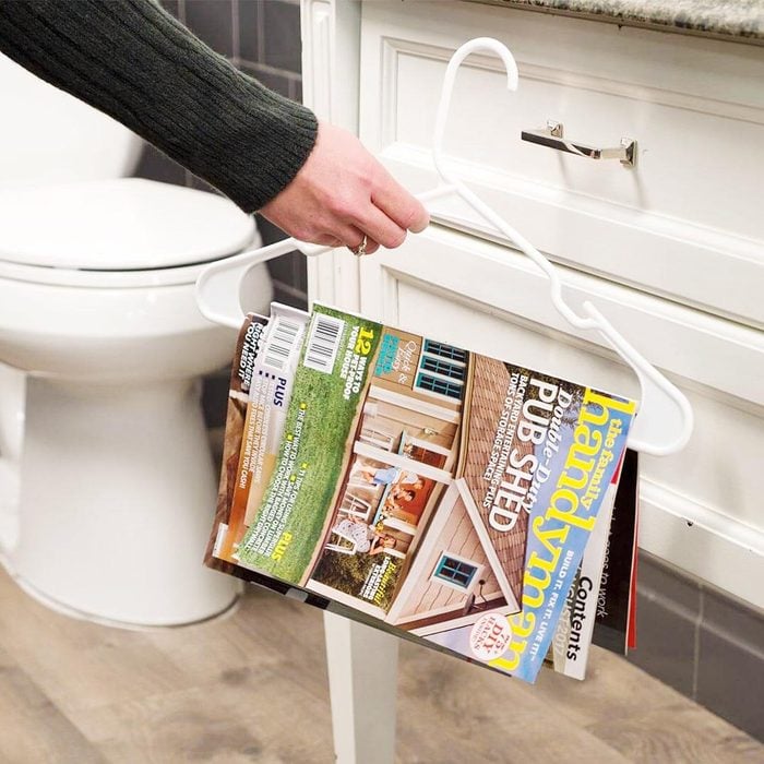 using a clothes hanger to hang magazines in a bathroom