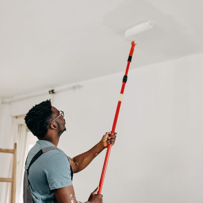 African-American professional painter paints the ceiling indoors