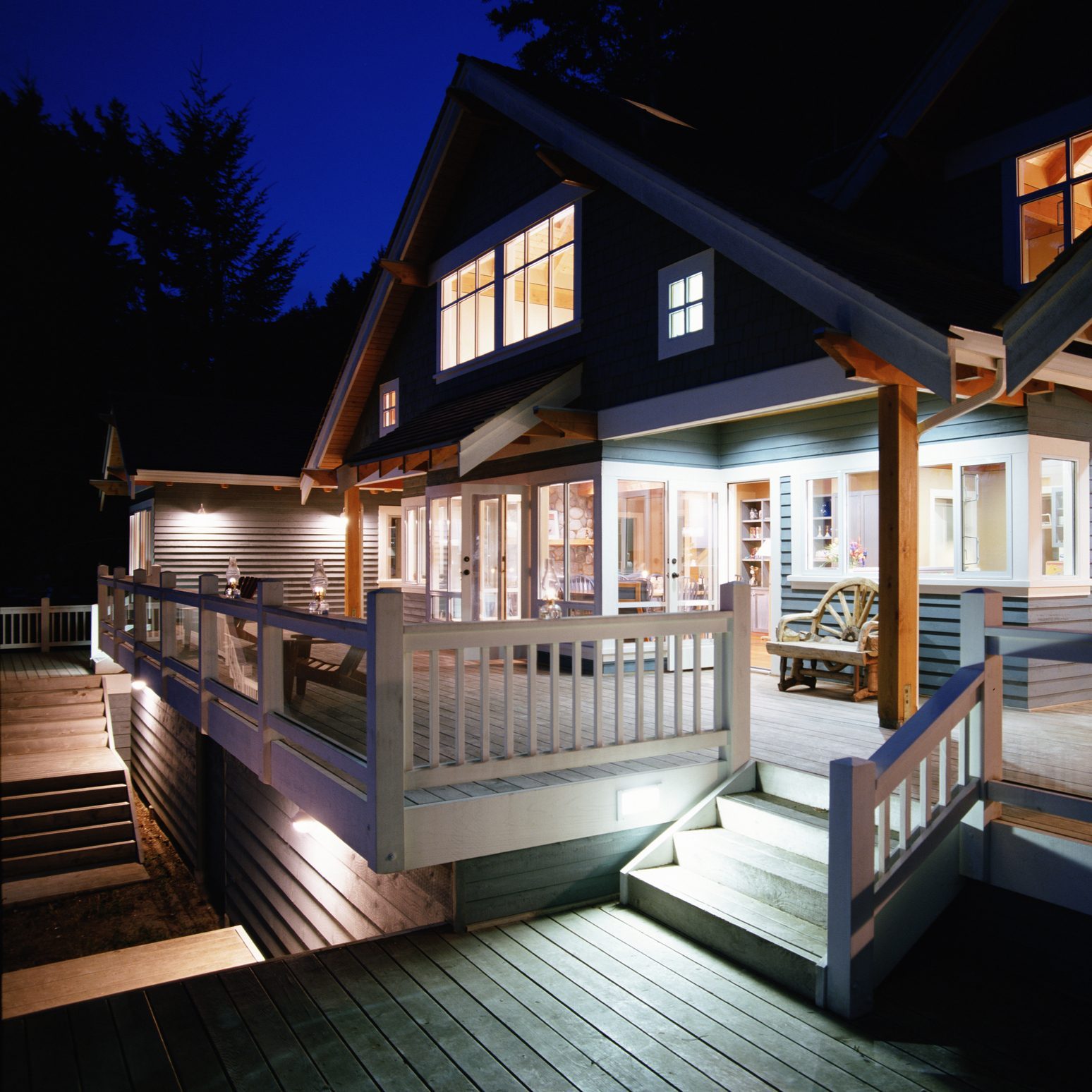 Exterior of house with entrance, decks, and window lit, night