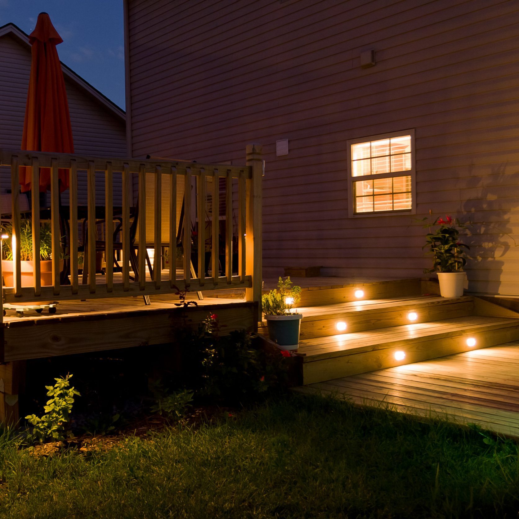 Wooden deck and patio with stair lights of family home at night