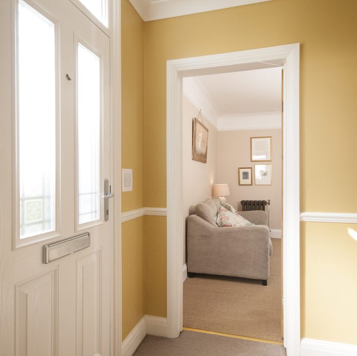 Hallway entrance into a home with a couch in a living room through an open doorway