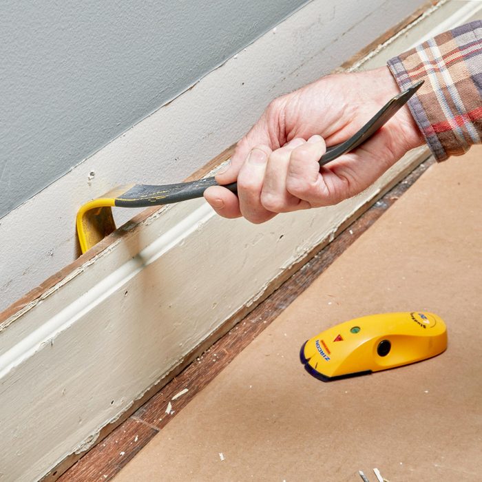using a pry bar to remove baseboard
