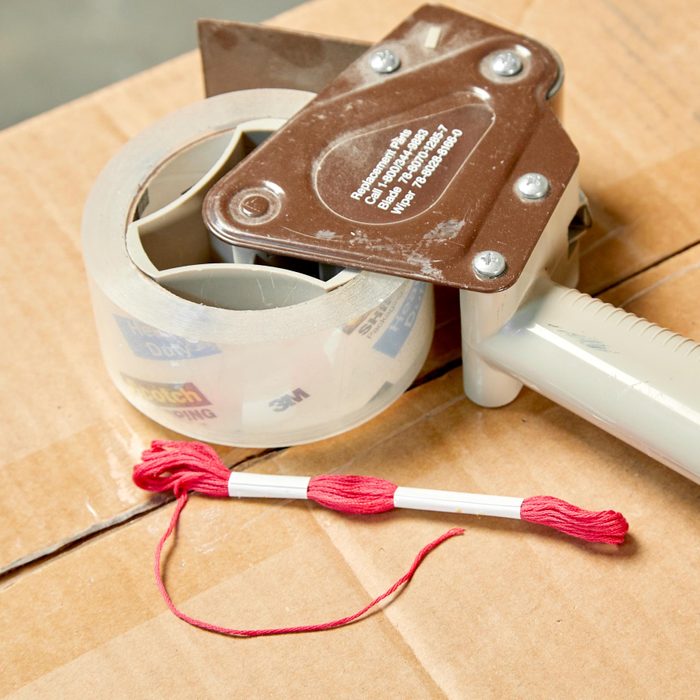 a roll of packing tape and some string on top of a cardboard box
