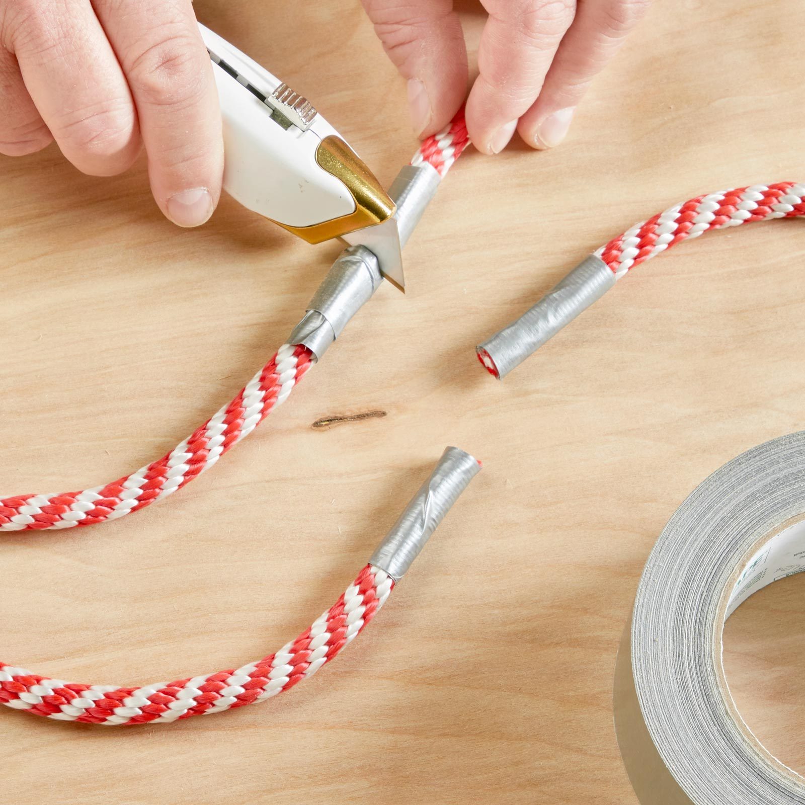 person cutting a piece of rope with duct tape at the end